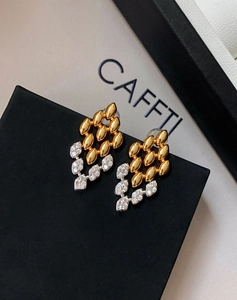 Vue macro de boucles d'oreilles feuilles dorées avec franges strassées sur support