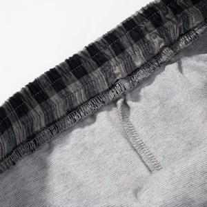 Detail of grey linen texture fabric and black plaid elastic waistband with neat stitching