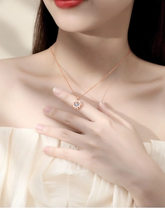 Detail shot of a rose gold dancing heart necklace with moissanite on a model neck
