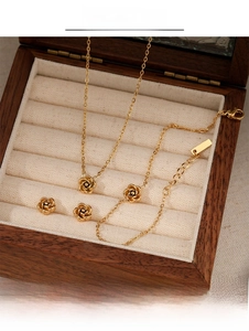 Detailed view of golden rose jewelry set including necklace and earrings in a wooden box