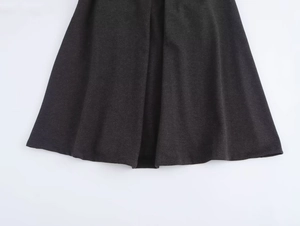 Detailed macro shot of the black woolen fabric texture and A-line hem of the midi skirt