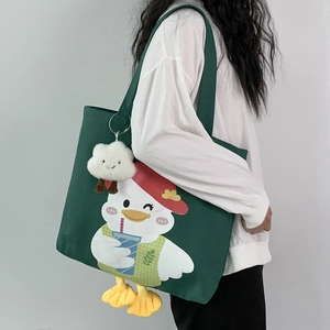 Detail of dark green canvas duck tote bag with white fluffy cloud charm on a model's shoulder