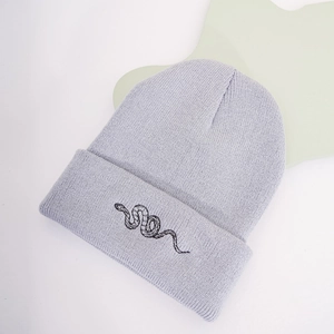Detail of lavender knit beanie featuring a minimalist black snake embroidery on the cuff