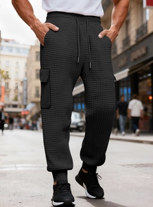Detail of men's black cargo joggers with waffle texture fabric and side pocket design