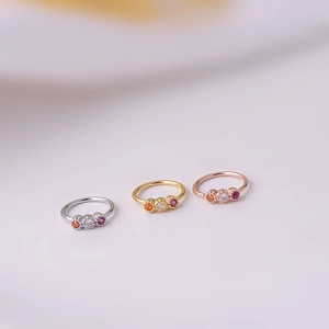 Detailed view of silver, gold, and rose gold nose rings set with vibrant colored zircons