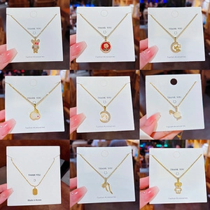 Collection of nine gold-plated necklaces with various charms like bunnies and moons