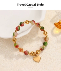 Detail of beaded bracelet with red-green gradient stones and golden heart charm