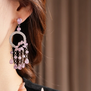 Close-up of luxury tassel earrings with pink and purple zircons on a female model