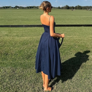 Deep blue backless sundress featuring a pleated flowing hem on a lush green lawn