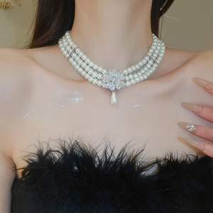 Detail of multi-layer pearl necklace with a sparkling clover pendant on a model