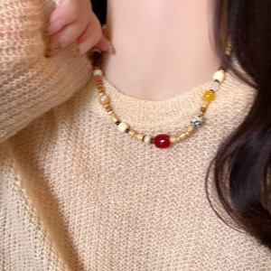 Ethno-Perlenkette mit Achat und Kokosnussschale auf einem beigen Strickpullover