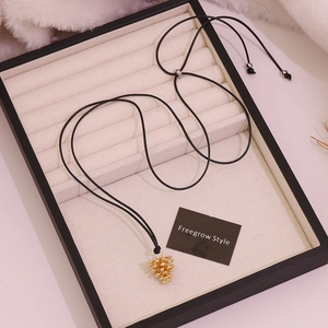 Close-up of golden pine cone pendant showing realistic texture on soft white fur