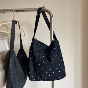 Close-up of denim shoulder bags with polka dot patterns and vintage label hanging on rack