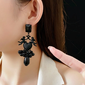 Macro shot of gothic angel heart earrings with black beads and charms on a model