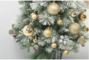 Detailed close-up of gold shiny and matte Christmas balls on a snow-covered pine tree.
