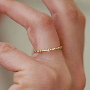 Vista macro di un anello a sfere dorate indossato per un look di gioielli minimalista