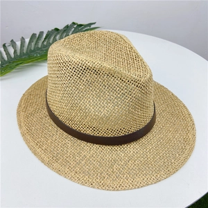 Close-up of woven straw hat texture with brown leather strap on a white surface