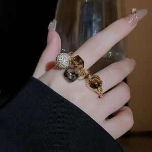Close-up of vintage gold rings with zircon and tiger eye stone worn by a model