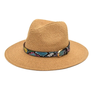 Close-up of woven straw hat with vibrant snakeskin pattern band and gold buckle detail