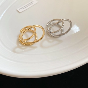 Detailed view of layered geometric open rings in gold and silver finish on white porcelain