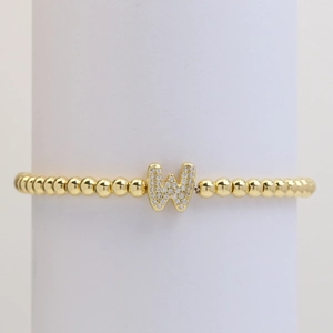 Macro view of gold beaded elastic bracelet with a micro-pave letter W charm detail