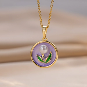 Macro view of floral enamel pendant with pearl center and green leaf details