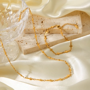 Goldene Edelstahl-Halskette mit Kreuzen und verstellbarem Verschluss auf Seidenhintergrund