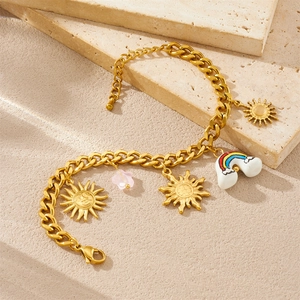 18K gold plated stainless steel bracelet with sun and rainbow cloud charms on sand