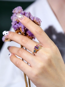 Close-up of 18K gold plated ring with cluster of colorful gemstones held with flowers