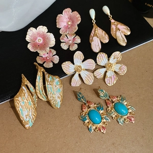 Detailed flat lay of colorful floral and geometric earrings with enamel and gems