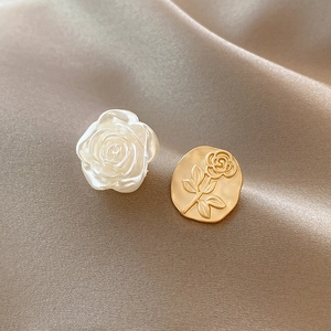 Detailed close-up of asymmetric rose earrings with white resin pearl and gold metal disc
