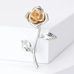 Detailed close-up of a vintage bicolored rose brooch with gold petals and silver stem