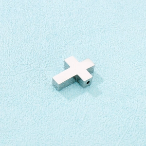 Close-up of polished stainless steel cross pendant with side hole for DIY jewelry making
