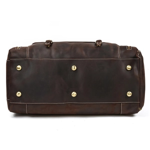 Detail of vintage leather duffel bag base featuring six protective gold metal feet studs