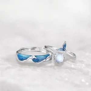 Dolphin whale tail couple rings with blue enamel and moonstone in snowy setting