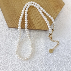 Detail of freshwater pearl necklace featuring gold lobster clasp and adjustable extension chain