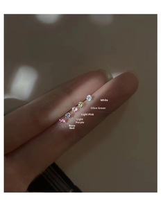 Detail view of five multi-colored mini silver stud earrings held on a fingertip
