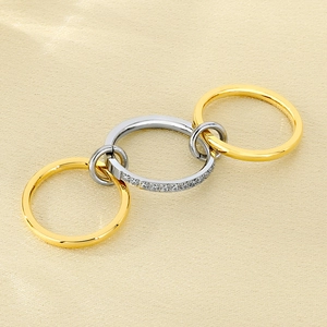 Close-up of interlocking gold and silver rings with zircon crystals on silk fabric