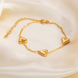Detail of 18K gold-plated bracelet featuring three heart charms and lobster clasp