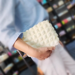 Detailed texture of a cream puff-style waffle cosmetic bag carried by a model