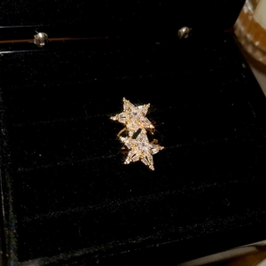 Macro shot of gold star-shaped zircon ear clips on black velvet jewelry box lining