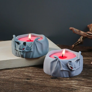Detail view of lit bat-shaped candle holder with red wax in gothic halloween setting