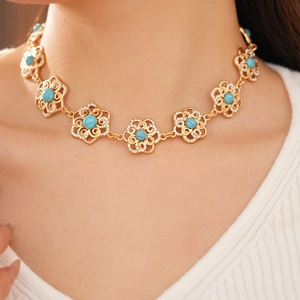 Macro view of vintage gold necklace with hollow flower links and turquoise stones