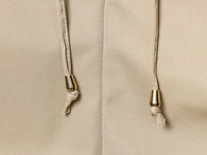 Detalle macro del cordón del vestido caqui con puntas de metal dorado pulido