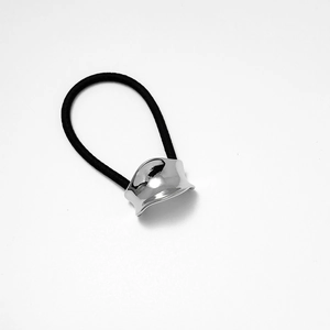 Dettaglio di un elastico per capelli nero con un ornamento in metallo argentato lucido