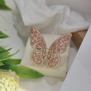 Close-up of golden butterfly ring with pink rectangular gems and white sparkling crystals