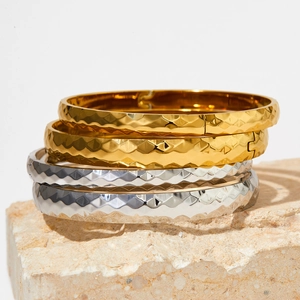 Macro view of gold and silver faceted stainless steel bangles on stone base