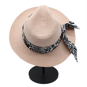 Close-up of fine straw weave texture and black paisley ribbon bow on a Panama sun hat