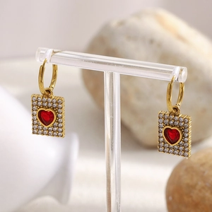 Macro shot of 18K gold plated earrings featuring red hearts and pavé crystals on a rectangular tag