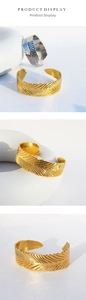 Dettaglio macro della trama piuma su bracciali a polsino spessi in oro e argento